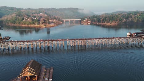 The-beautiful-Khwae-Noi-River-with-the-Mon-and-Songkalia-bridges-in-the-background,-creating-a-picturesque-scene-in-Songklaburi,-Thailand