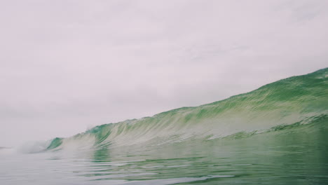 Wide-angle-view-of-wave-slowly-rising-glowing-green-into-barrel-with-clear-water