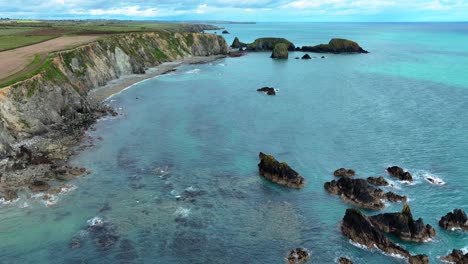 Drone-establishing-shot-of-sheltered-bay-with-crystal-clear-water-coastline-of-Waterford-Ireland