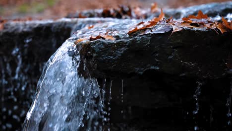 SLOWMOTION:-Water-flowing-over-rocks-forming-a-waterfall-in-autumn