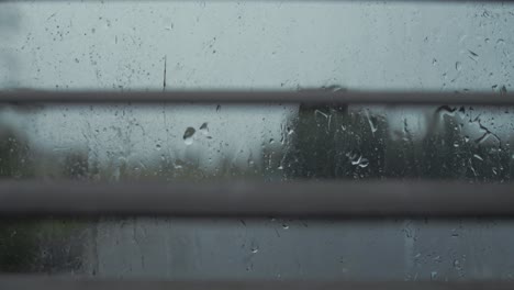 Raindrops-rolling-down-window-looking-through-blinds