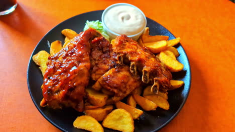 Primer-Plano-Plato-Servido-Gajos-De-Papa-Con-Costillas-De-Res-Mayonesa-Salsa-De-Tomate-Mesa-De-Comedor-Naranja-En-El-Restaurante-Con-Bebida-De-Cola