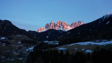 Drone-view-of-Dolomites-mountains-in-Italy-at-sunset-with-snow,-peaks,-landscape,-light-reflections,-and-forests