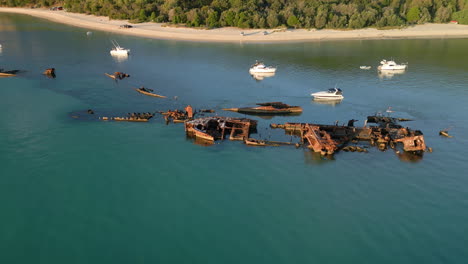 Old-Oxidized-ship,-shipwreck-Drone-closeup-view,-zoom-into-decayed-artifact-floating-in-Tangalooma-Moreton-Island,-white-sand-beach-coastline