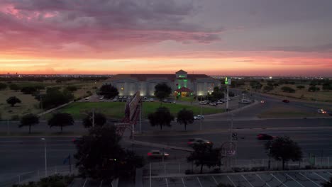 Drone-image-of-a-sunset-over-a-bustling-shopping-mall-and-busy-avenue-in-Reynosa,-Mexico