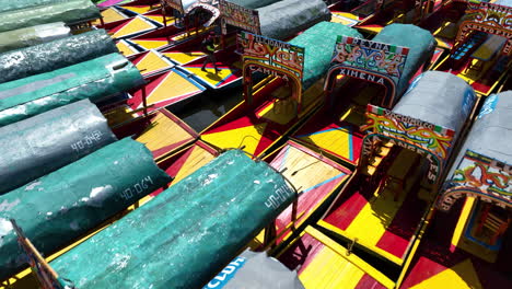 Aerial-view-low-over-Trajinera-boats-at-the-Xochimilco-Lake,-in-sunny-Mexico