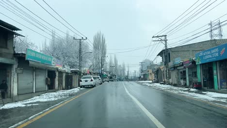 Car-driving-on-a-road-in-Skardu-City-in-landscape-covered-with-snow---It-is-cloudy