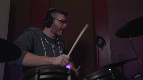 a-drummer-wearing-headphones-jams-in-a-recording-studio-as-his-band-records-music