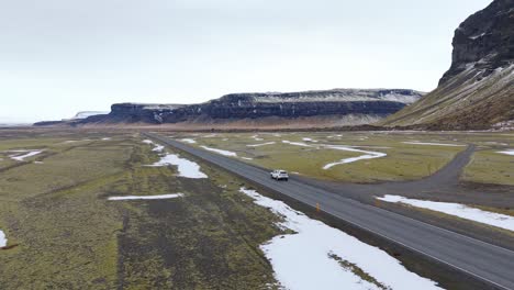 Panoramadrohne-Folgt-Weißem-Lieferwagen-Auf-Fahrt-Durch-Isländische-Berglandschaft