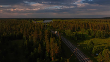 Aerial-view-following-a-RV-driving-in-middle-of-sunlit-forests-of-Lapland