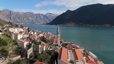 4K-drone-footage-captures-Saint-Nicholas-Church-in-the-charming-town-of-Perast,-Montenegro,-with-a-beautiful-view-of-the-UNESCO-listed-turquoise-Bay-of-Kotor-and-mountains-in-the-background