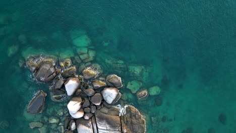 Top-down-drone-view-of-rocks-in-ocean---rising