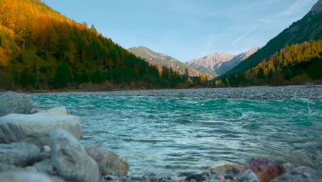 Agua-Azul-Clara-Del-Río-De-Montaña-Corriendo-Por-Pintorescos-Y-Coloridos-árboles-Otoñales-Bajo-El-Sol-De-La-Tarde,-Alpes-Austriacos