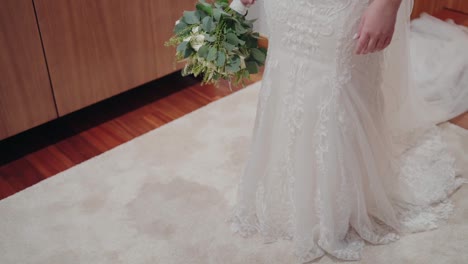 Bride-in-lace-gown-holding-a-bouquet,-partial-view