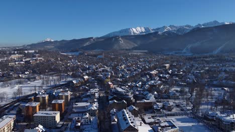 Aerial-view-over-Zakopane-town-and-Main-Street,-with-snowy-Tatra-mountains-in-the-background---Poland