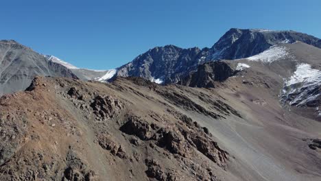 Vista-Aérea-De-Los-áridos-Picos-De-Las-Montañas-Alpinas-Con-Polvo-De-Nieve.