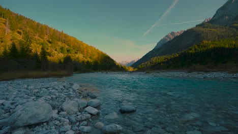 Agua-Azul-Clara-Corriendo-Por-Pintorescos-Y-Coloridos-árboles-Otoñales-Bajo-El-Sol-De-La-Tarde,-Alpes-Austriacos