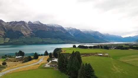 Panorámica-Aérea-De-Transporte-Por-Carretera-Sobre-Tranquilas-Colinas-Con-Vistas-Al-Lago-Wakatipu.