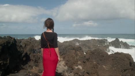 Woman-admires-the-huge-waves-crashing-on-the-rocky-shore
