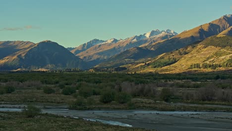 Lowland-forests-cut-across-by-shallow-rivers-with-sunlight-dancing-on-moutains-in-Glenorchy