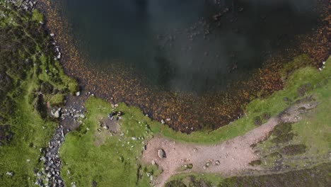 Vista-Aérea-De-Dos-Excursionistas-Sentados-En-Blueberry-Tarn,-Lake-District---Reino-Unido