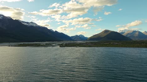 Panoramic-aerial-establishing-of-golden-light-reflecting-across-clouds-onto-Lake-Wakatipu-with-Glenorchy-lowlands-behind