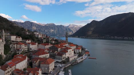 4K-drone-shot-captures-the-charming-town-of-Perast,-Montenegro,-with-a-beautiful-view-of-Saint-Nicholas-Church,-the-UNESCO-listed-Bay-of-Kotor,-and-mountains-in-the-background