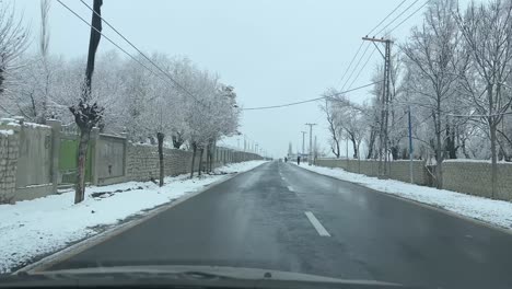 Car-driving-on-a-road-in-Skardu-City-in-landscape-covered-with-snow---It-is-cloudy
