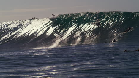 Surfers-barely-makes-it-over-wave-crest-as-water-crashes-in-shimmering-display-of-strength