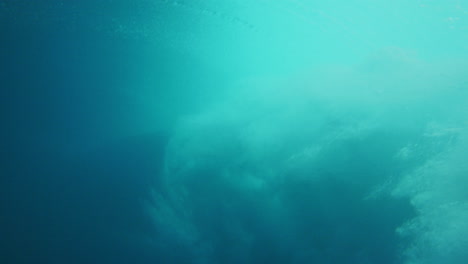 Bubbling-ocean-water-sprays-across-surface-as-vortex-turns,-underwater