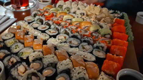 Teller-Mit-Vielen-Verschiedenen-Sushi-Zum-Abendessen,-Handheld-Zoom-Aufnahme