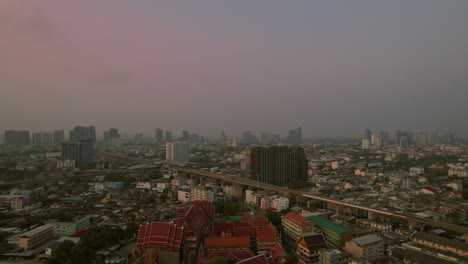 Luftaufnahme-Der-Stadt-Bangkok-Bei-Sonnenuntergang-Mit-Den-Roten-Dächern-Eines-Buddhistischen-Tempels