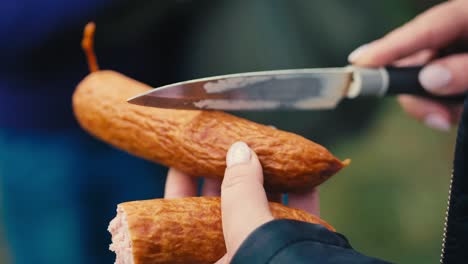 Woman-makes-cuts-on-a-sausage-with-a-knife