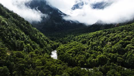 Sunlight-shines-down-on-tropical-forest-and-winding-river-valley-with-low-clouds-across-mountains