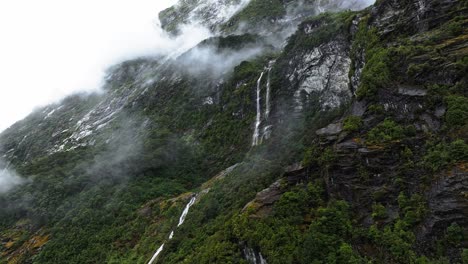 Wasserfälle-Sprudeln-Entlang-Der-Klippenränder-Des-Milford-Sound-Mit-Tief-Hängenden-Wolken-über-Dem-Wald