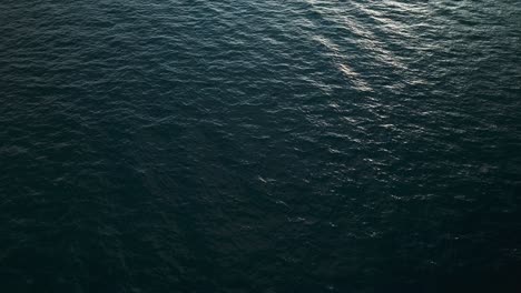 Aerial-top-down-descends-on-serene-water-texture-with-glow-of-sunset