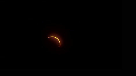 Shortly-after-totality,-a-thin-crescent-outline-of-sunlight-travels-across-the-sky-during-a-total-solar-eclipse