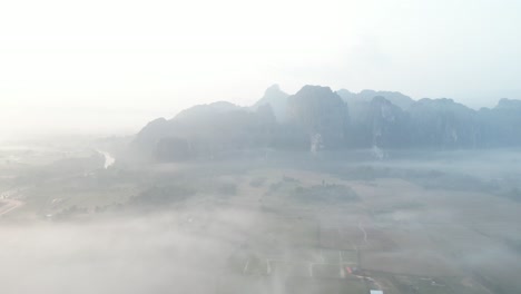 Luftaufnahme-Eines-Nebligen-Morgennebels-über-Dem-Fluss-In-Vang-Vieng,-Der-Abenteuerhauptstadt-Von-Laos