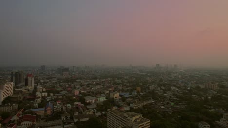 Aerial-establishing-pink-smog-skyline-at-dusk-Bangkok,-Thailand