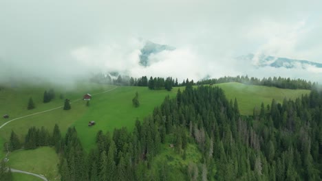 Un-Dron-Vuela-Sobre-Una-Exuberante-Colina-Verde-Cubierta-De-Nubes
