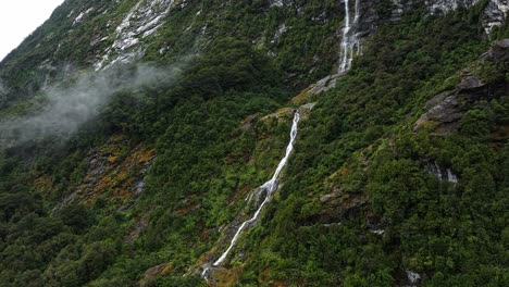Aerial-parallax-of-thin-tendril-of-waterfall-cascading-down-scenic-mountains-in-New-Zealand