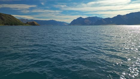 Luftaufnahme-Des-Dolly-über-Dem-Glitzernden-Wasser-Des-Lake-Hawea-An-Einem-Schönen-Sommertag