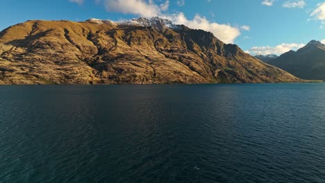Atemberaubende-Rote-Felsen-überblicken-Den-Lake-Wakatipu-Mit-Schneebedeckten-Gipfeln-über-Dem-Wasser