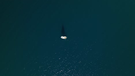Drohnen-Übersicht-Von-Oben-Nach-Unten-über-Segelboot-Und-Segelschatten-Auf-Dunklem-Wasser