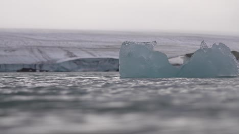 Floating-Ice-in-Cold-Sea-Water-Under-Glacier,-Cinematic-Low-Angle-Slow-Motion