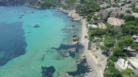 Aerial-flyover-Mallorca-coastline-with-beautiful-clear-waters-and-hotels-perched-on-hillside