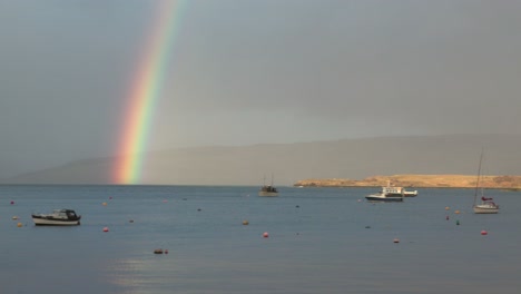 Slow-panning-shot-of-a-vibrant-double-rainbow-over-the-harbour-at-Tobermory