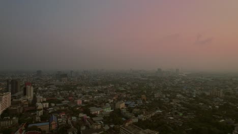 Hazy-dusk-over-Bangkok's-sprawling-cityscape---aerial-flyover