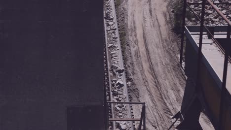 conveyor-belt-transports-crushed-stones-alongside-a-dirt-road-in-a-quarry