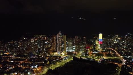 Panoramic-drone-shot-in-front-of-illuminated-downtown-of-Bogota,-night-in-Colombia